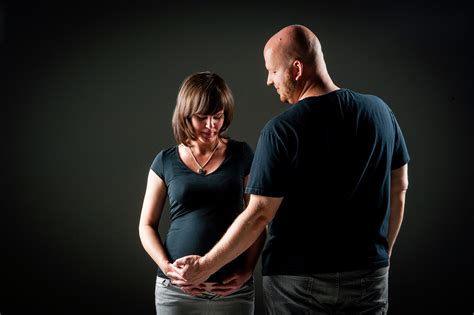 Ein Paar betrachtet liebevoll den bemalten Babybauch der Frau, während Fotos gemacht werden