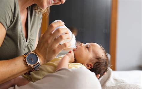 Baby wird von Elternteil liebevoll mit der Flasche gefüttert