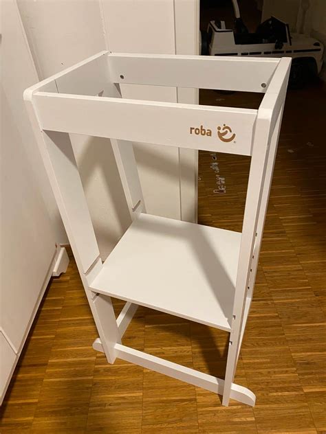 Illustration des roba Lernturms mit einem Kind, das auf der Standfläche steht und in die Küche blickt.