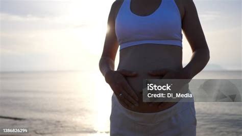 Bild einer schwangeren Frau, die sanft ihren Bauch streichelt, mit einem Lächeln der Freude und des Staunens über die Kindsbewegungen.