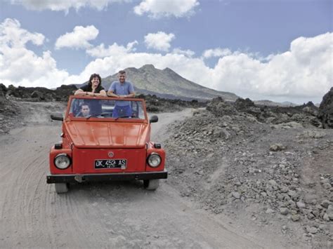 Zwei Personen in einem Buggy auf einer staubigen Offroad-Strecke mit üppiger Vegetation im Hintergrund