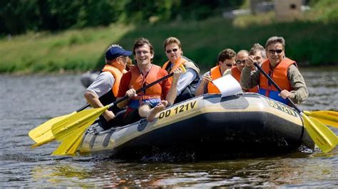 Eine Gruppe von Menschen in Schwimmwesten paddelt auf einem Fluss mit Stromschnellen in einem Schlauchboot