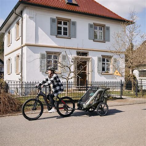 Grafik, die die unterschiedlichen Sitzpositionen und Blickrichtungen eines Kindes im Kinderwagen und im Fahrradanhänger vergleicht.