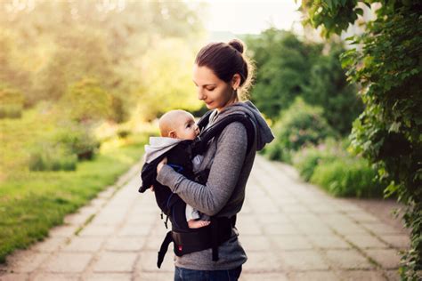 Illustration einer Mutter, die ihr Baby in einer ergonomischen Babytrage vorne trägt.