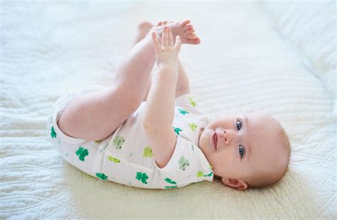 Ein Baby liegt auf dem Rücken und schaut auf ein buntes Mobile über sich.