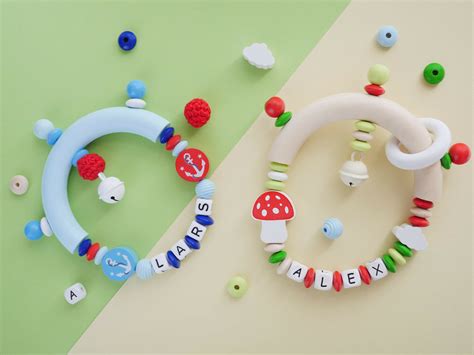 Beispiele für fertiggestelltes Babyspielzeug, wie Schnullerketten und Greiflinge, mit eingearbeiteten Silikon-Eulenperlen.