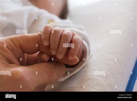 Nahaufnahme einer winzigen Babyhand, die den Daumen umgreift