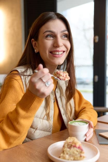 Foto einer lächelnden Nela, die am Tisch sitzt und Kuchen isst, ihre linke Hand leicht verkrampft auf dem Tischset.