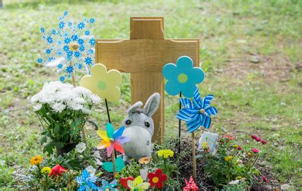 liebevoll gestaltetes Grab eines Sternenkindes mit Spielzeug und Blumen