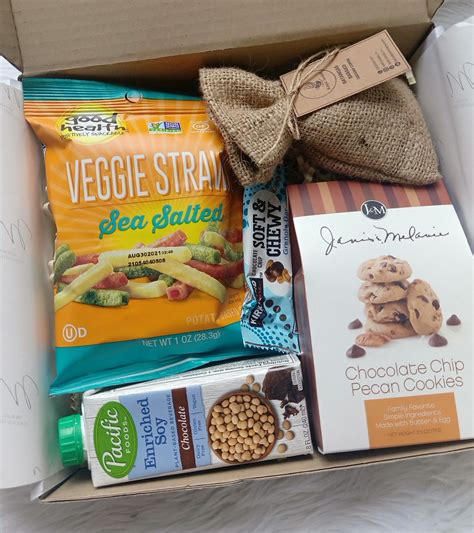 Eine liebevoll zusammengestellte Geschenkbox mit verschiedenen gesunden Snacks, Tee und einer kleinen Klappbox.