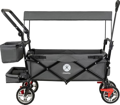 Mann schiebt einen faltbaren Bollerwagen mit zwei Kindern darin.