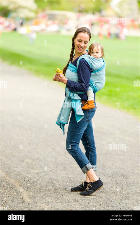 Mutter trägt ihr Kleinkind auf dem Rücken in einem Tragetuch.