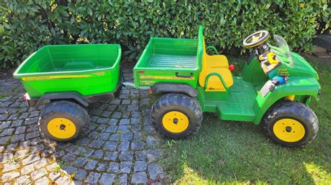 Detailaufnahme eines Peg Perego John Deere Elektro-Traktors mit seinem Anhänger.