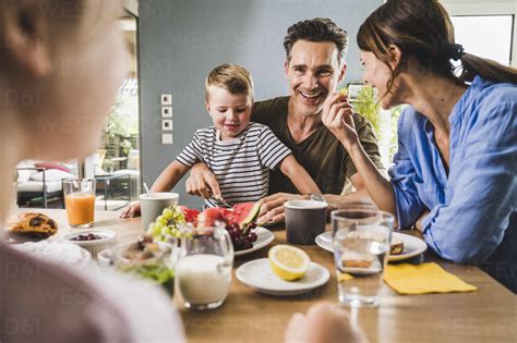 Familie beim gemeinsamen Frühstück, Kind isst begeistert