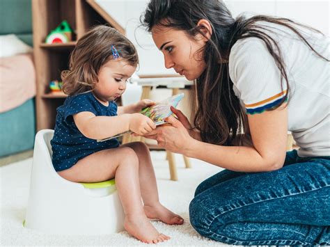 Erzieherin, die einem Kind geduldig beim Töpfchentraining hilft.
