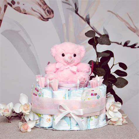 Eine wunderschön gestaltete Windeltorte für ein Mädchen, dekoriert mit rosa Bändern, Söckchen und einem Kuscheltier.