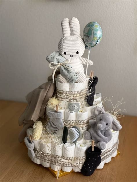 Detail einer personalisierten Windeltorte mit aufgesticktem Babynamen auf einem Schmusetuch.