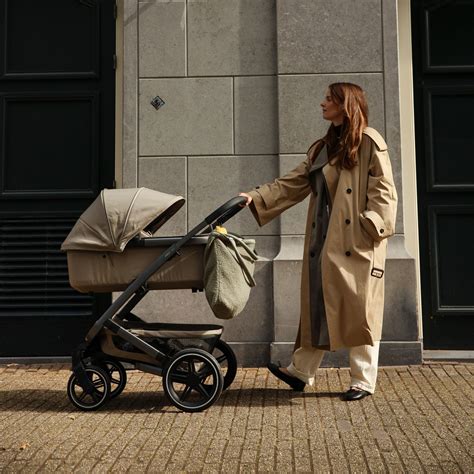 Illustration, die zeigt, wie der Joolz Fußsack an einem Joolz Kinderwagen befestigt wird und welche Funktionen (z.B. Gurtschlitze, Anti-Schlamm-Beschichtung) hervorgehoben werden