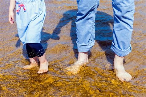 Ein Elternteil hält ein Baby im Wasser, beide lächeln.