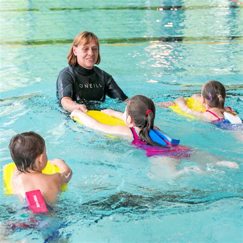 Kinder lernen spielerisch im Wasser unter Anleitung eines FLIPPER-Schwimmlehrers.