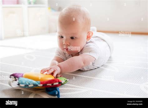 Nahaufnahme eines Babys, das mit den Händen nach Spielzeug an einem Spielbogen greift