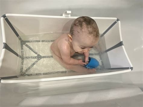 Kind spielt mit dem Stokke Flexi Bath Badespielzeug, einem Set aus bunten Bechern.