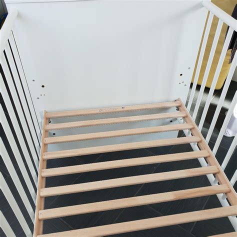 Illustration, die zeigt, wie Umbauseiten an einem Babybett montiert werden, um es in ein Juniorbett zu verwandeln.