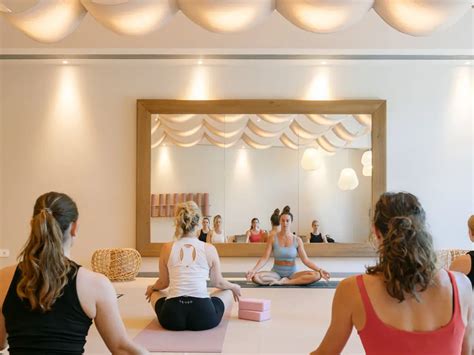 Eine Gruppe von Frauen praktiziert Yoga in einem hellen Raum, einige sind schwanger.