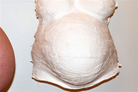 Gipsabdruck eines Babybauchs, der vorsichtig vom Körper abgenommen wird