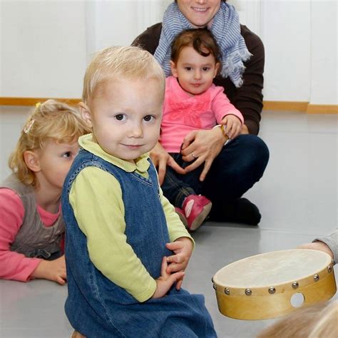 Eltern mit Kleinkindern singen und spielen in einem bunten Raum