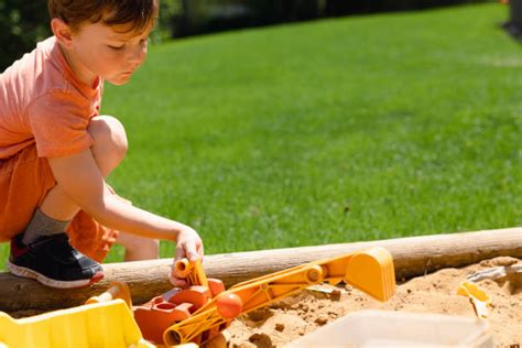 Kind spielt fröhlich mit Sandspielzeug im Sandkasten